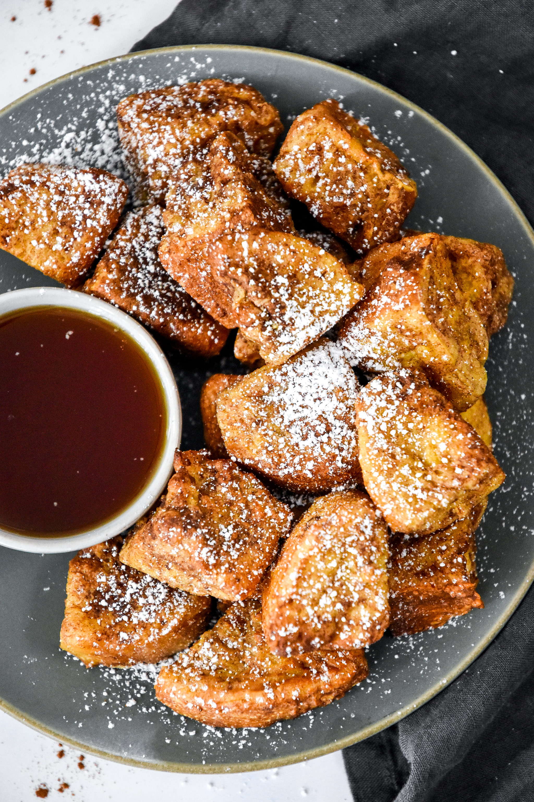 air fryer french toast bites on a plate with a cup of maple syrup.