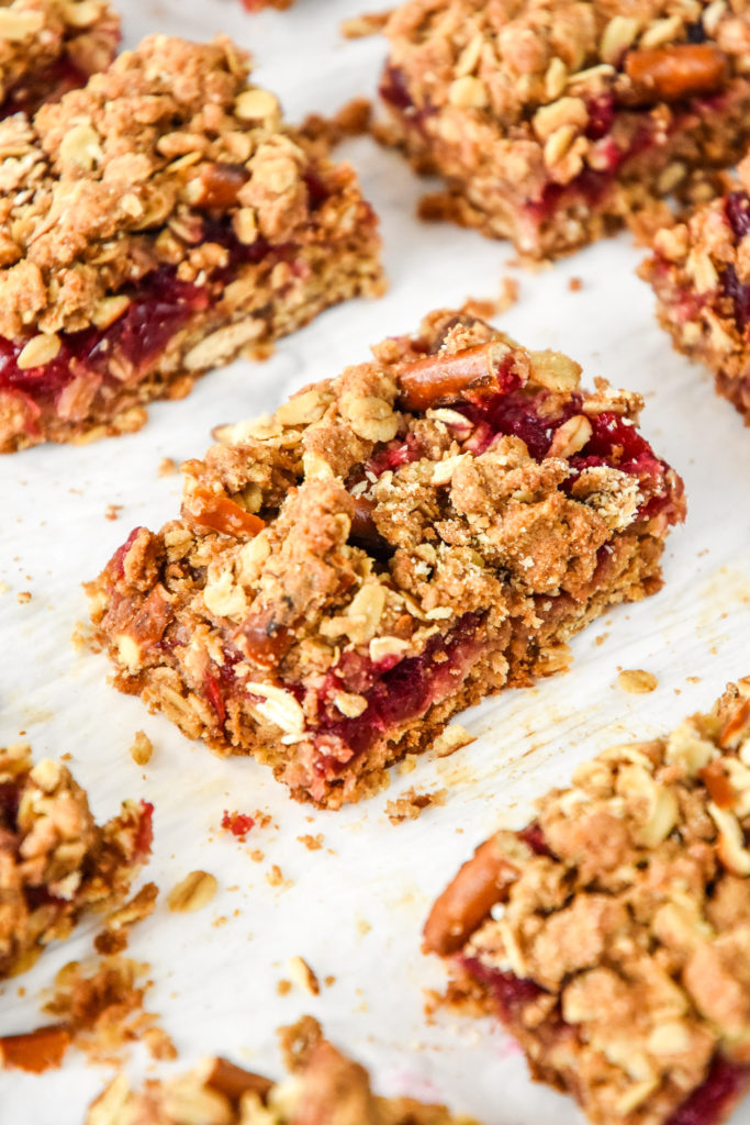 cooked and cut cranberry pretzel oat crumble bars on parchment paper.