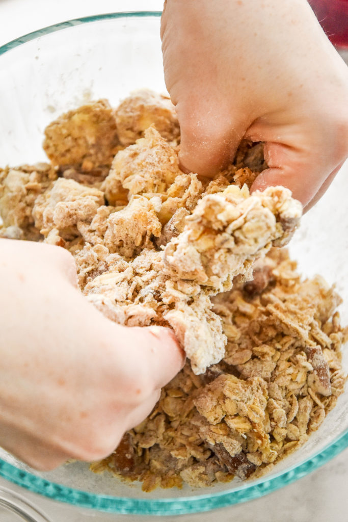 squishing the crumble mixture with hands to mix it together.