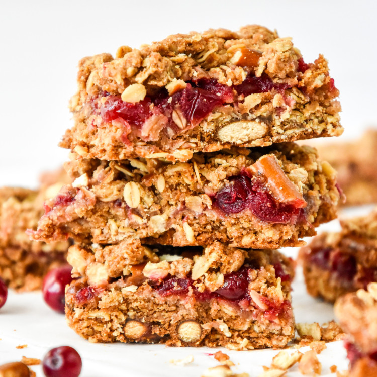stacked cranberry pretzel oat crumble bars on parchment paper.