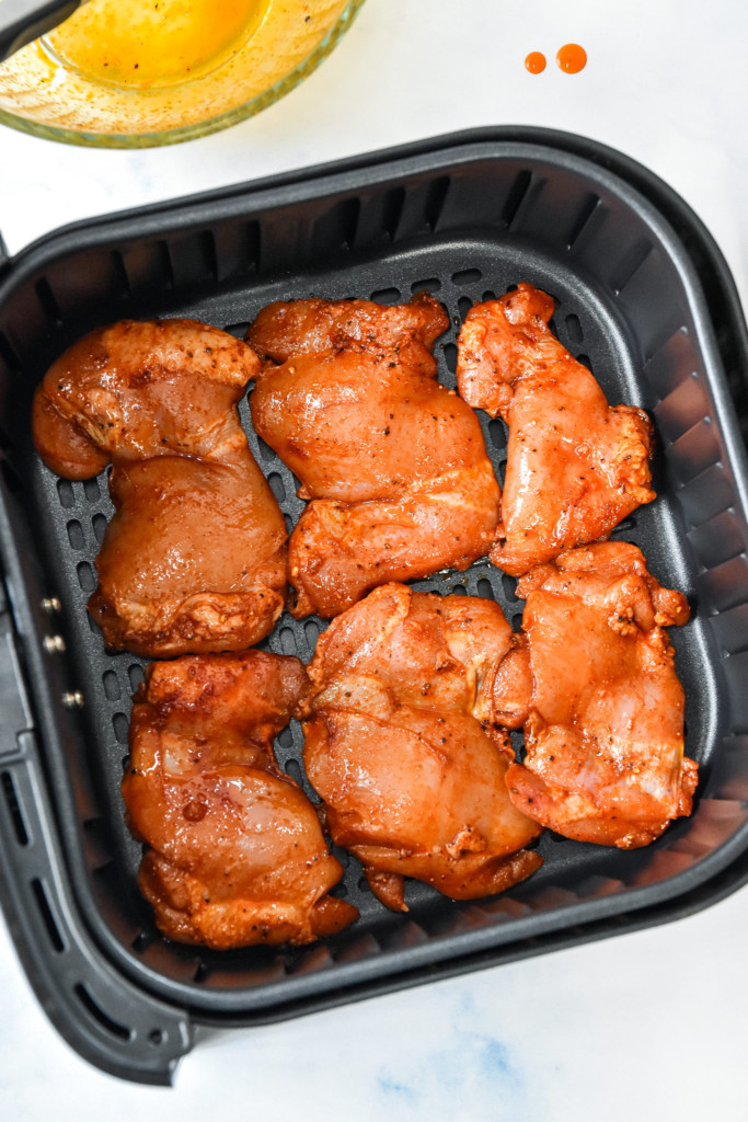 raw boneless chicken thighs in the air fryer basket.