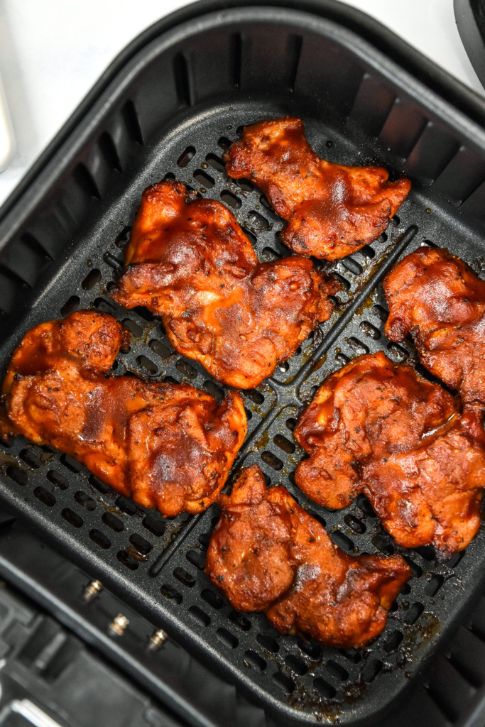 cooked air fryer bbq boneless chicken thighs in the air fryer basket.