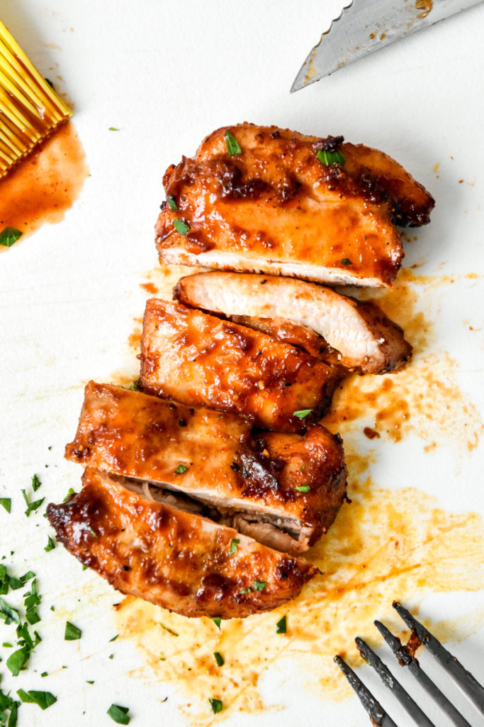 sliced air fryer boneless bbq chicken thighs on a cutting board.