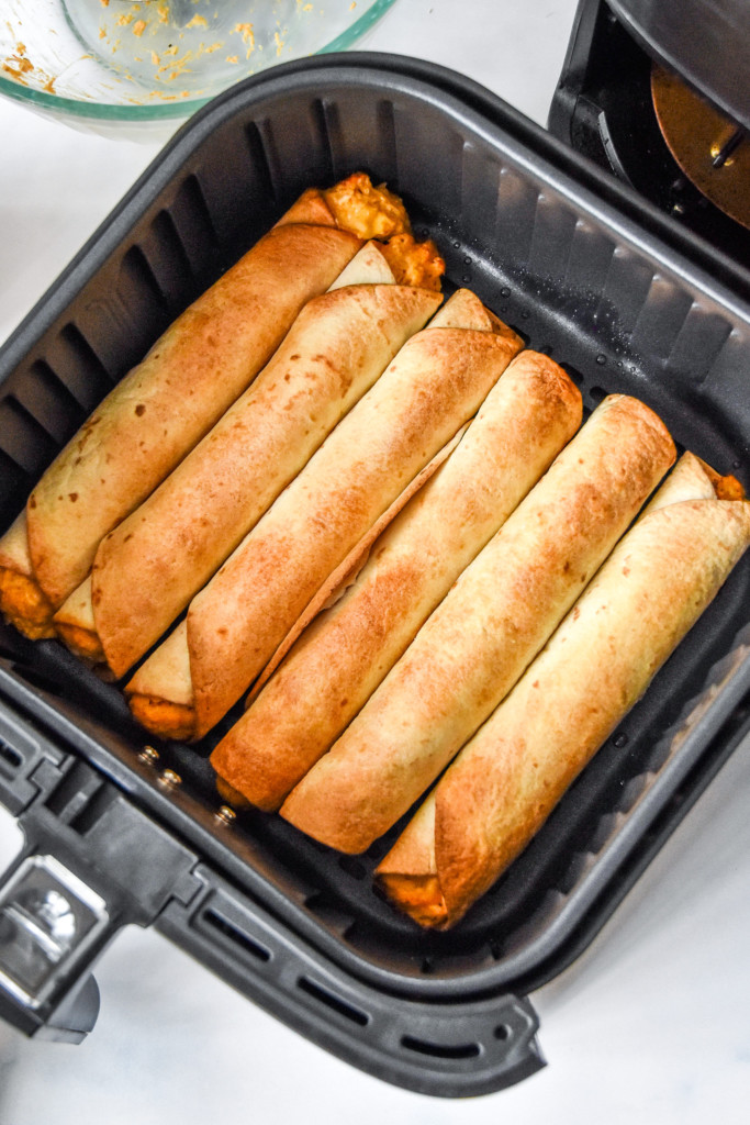 cooked air fryer buffalo chicken flautas in the air fryer basket.