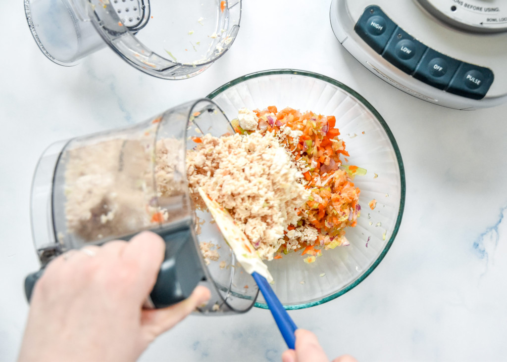 dumping shredded chicken into a glass mixing bowl.