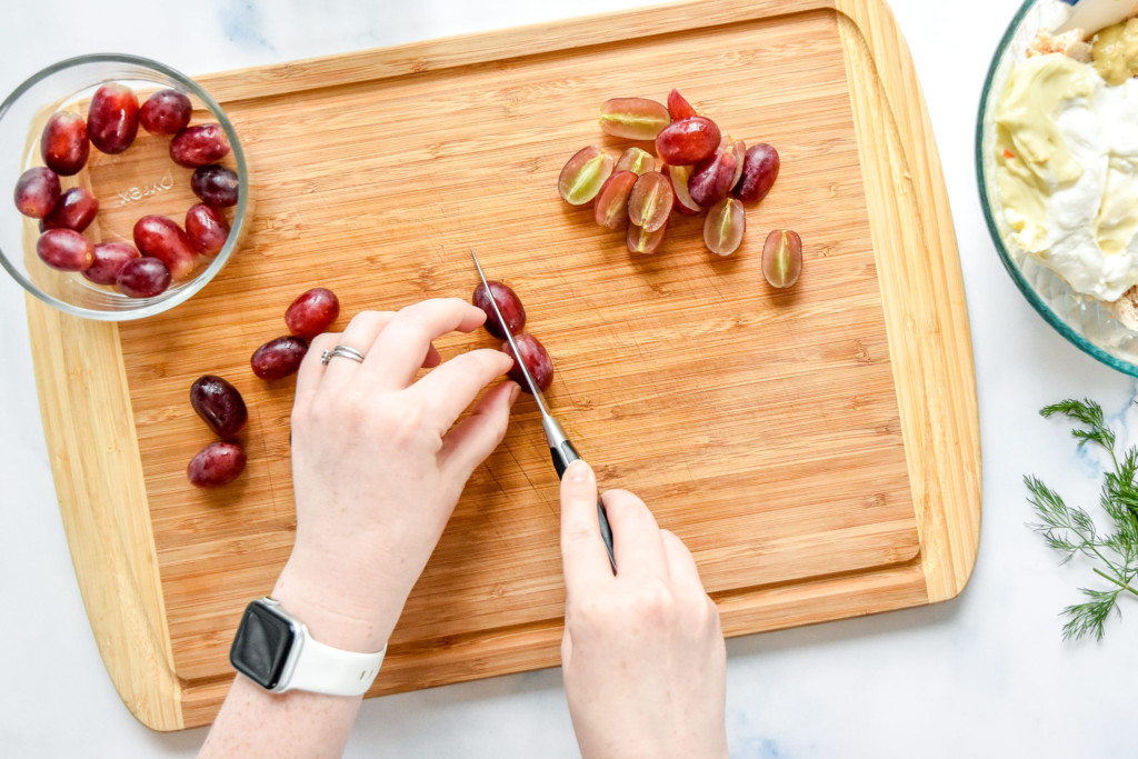 cutting grapes on a cutting board with a paring knife.