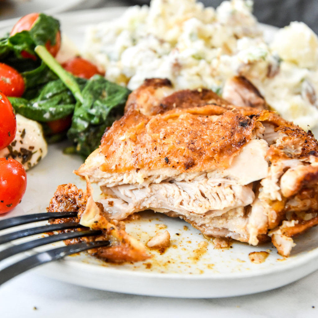 air fryer bone-in crispy chicken thigh cut into on a plate.