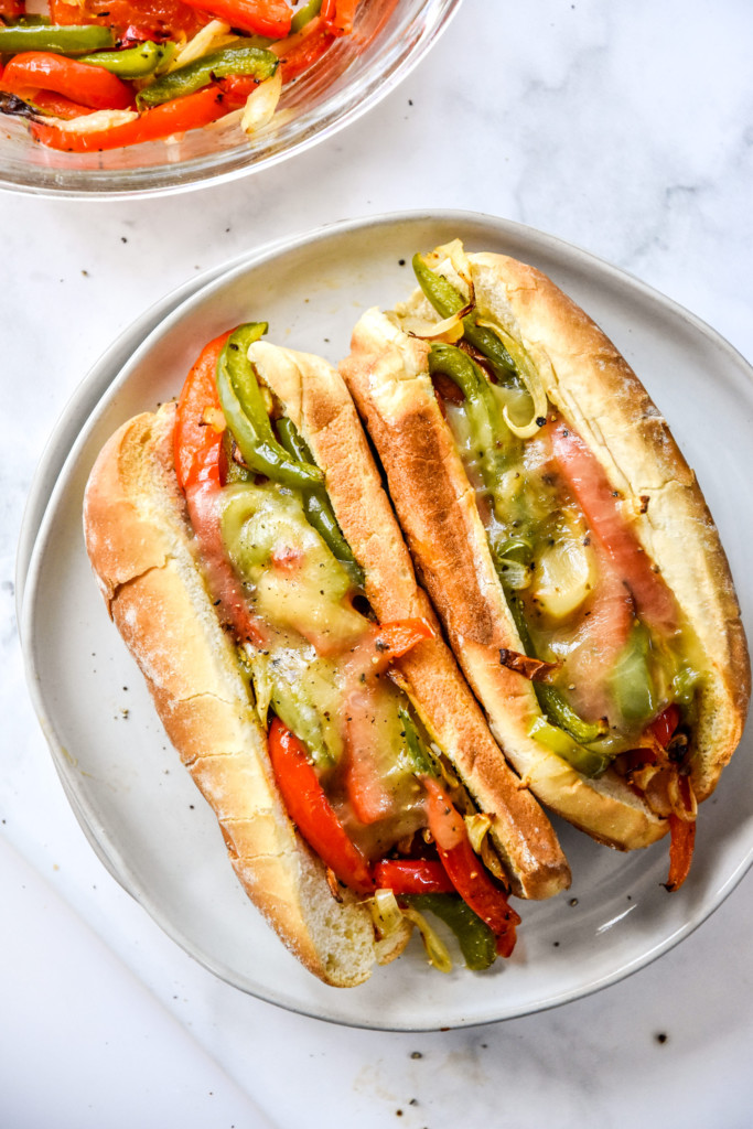 air fryer sausage dogs with peppers and onions on a plate ready to eat.