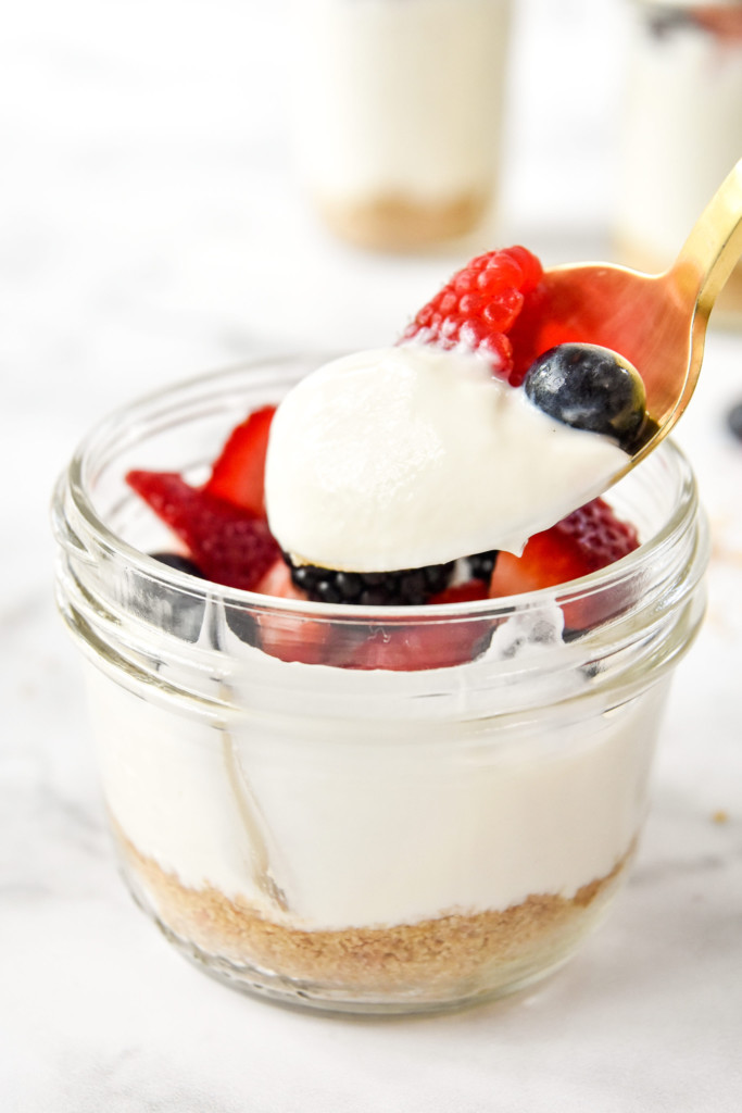 taking a bite of no-bake cheesecake yogurt cups on a spoon.