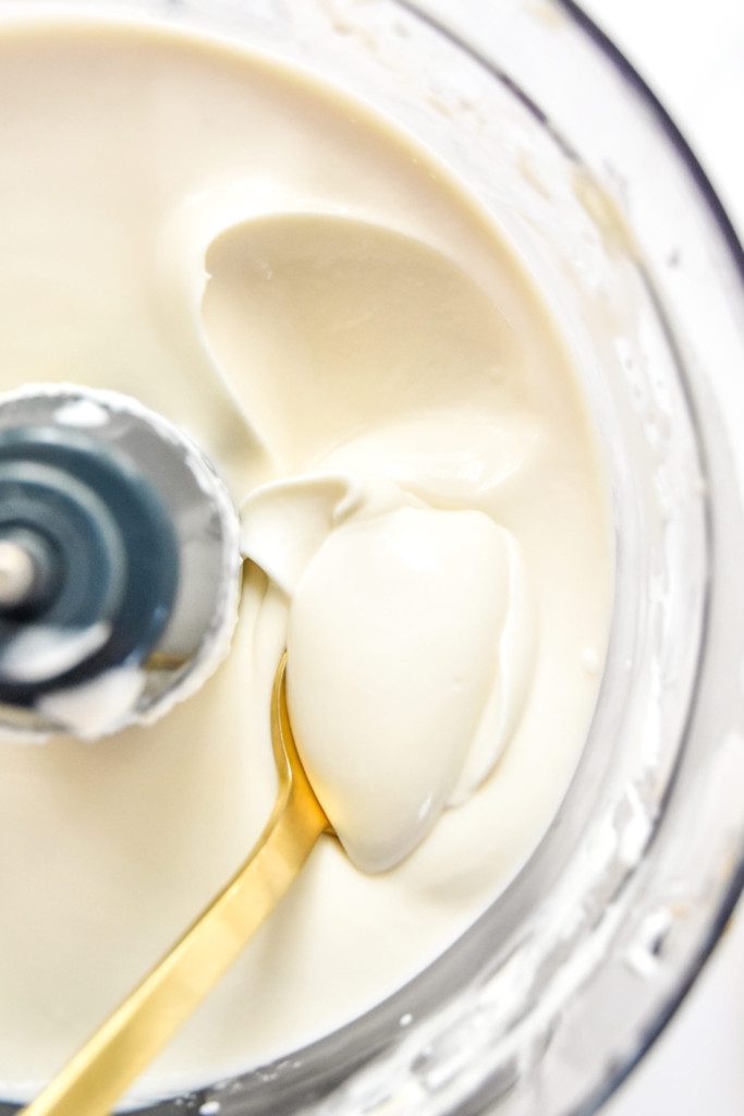 close up of inside the food processor with cheesecake yogurt filling and a spoon.