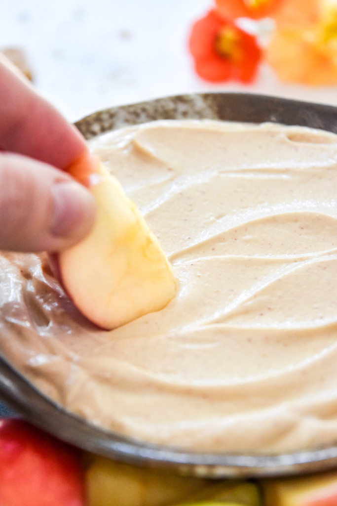dipping an apple into the peanut butter greek yogurt fruit dip.