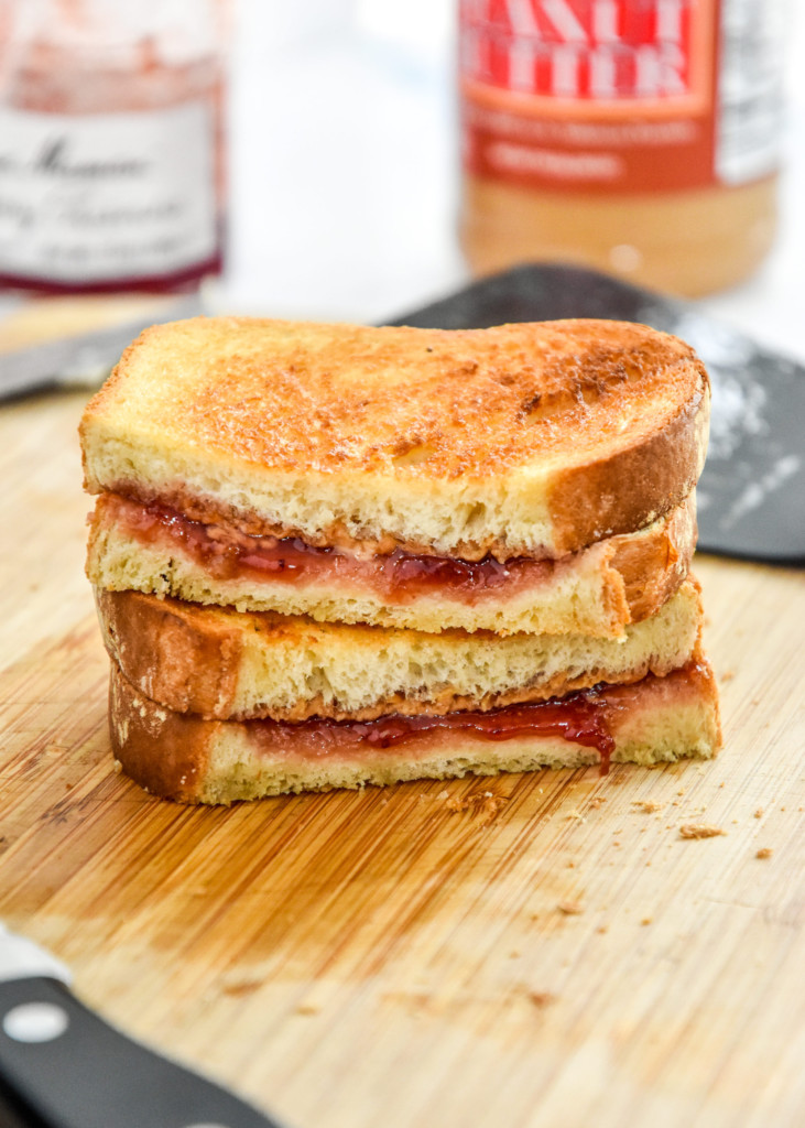 cut in half air fryer peanut butter sandwich stacked on a cutting board.