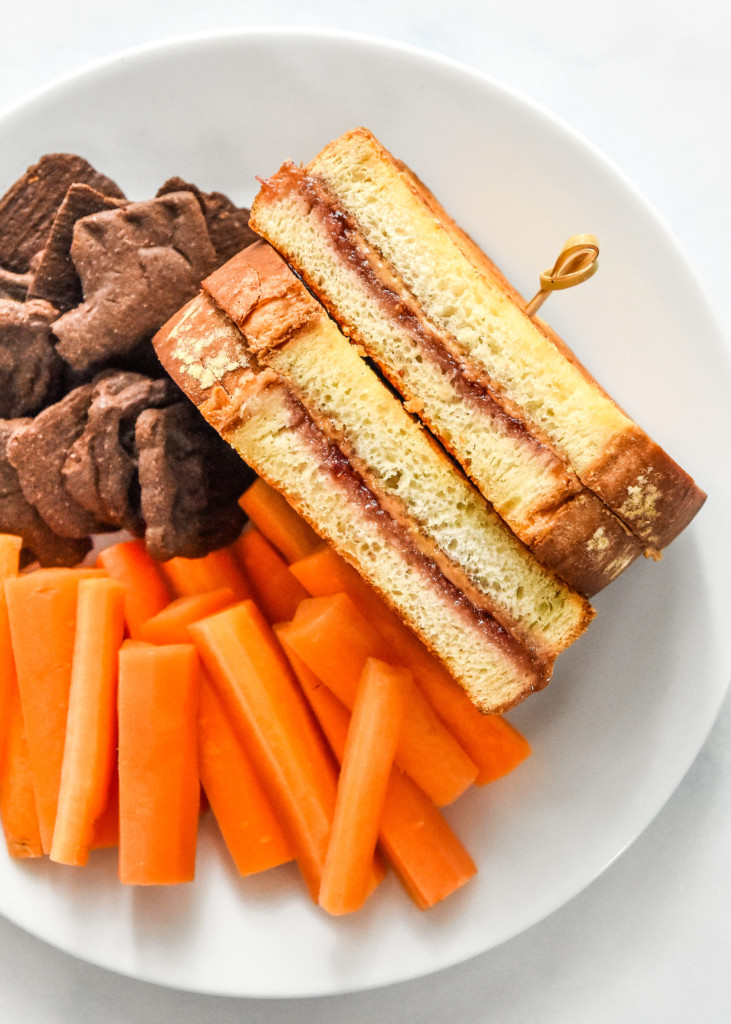 air fryer peanut butter sandwiches jelly version on a plate with carrot sticks and chocolate graham crackers.