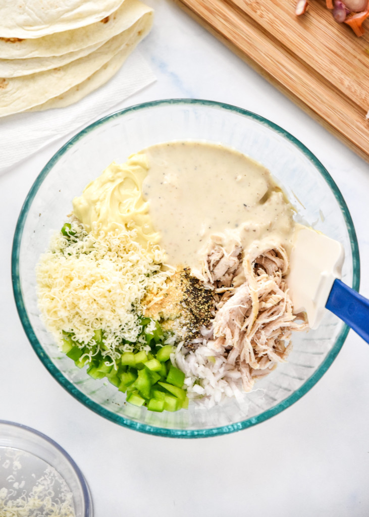 ingredients in a glass bowl for the caesar chicken salad lunch wraps before mixing.