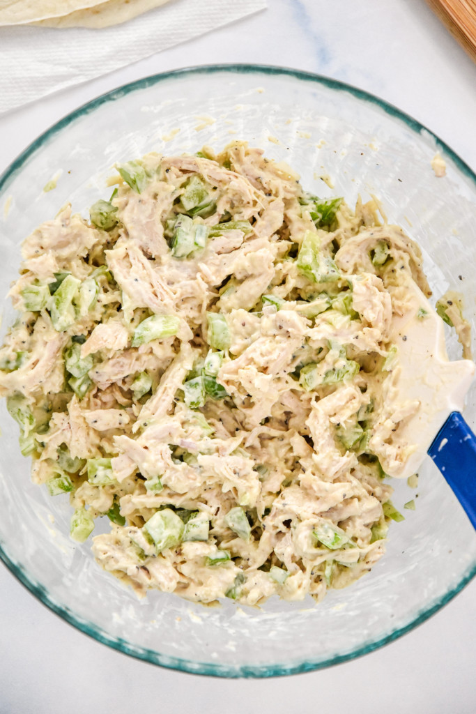 mixed up caesar chicken salad lunch wraps in a glass bowl.