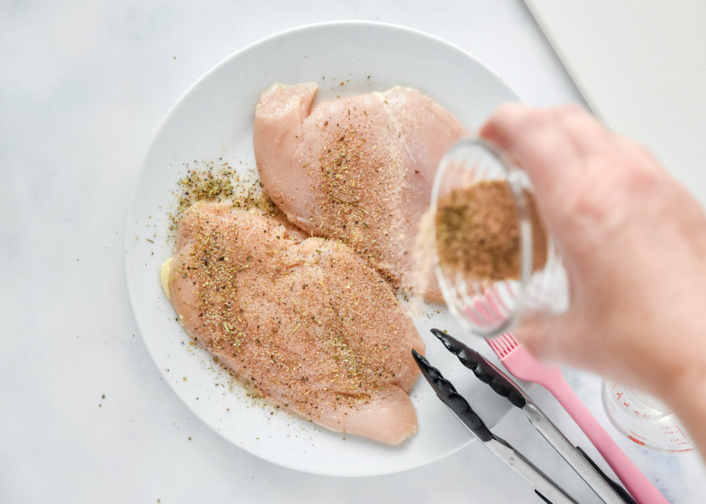 spreading seasoning on to the tenderized chicken.
