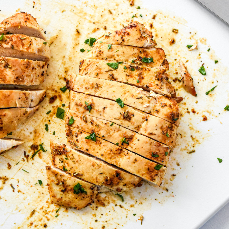 juicy air fryer chicken breasts cut into slices on a cutting board.