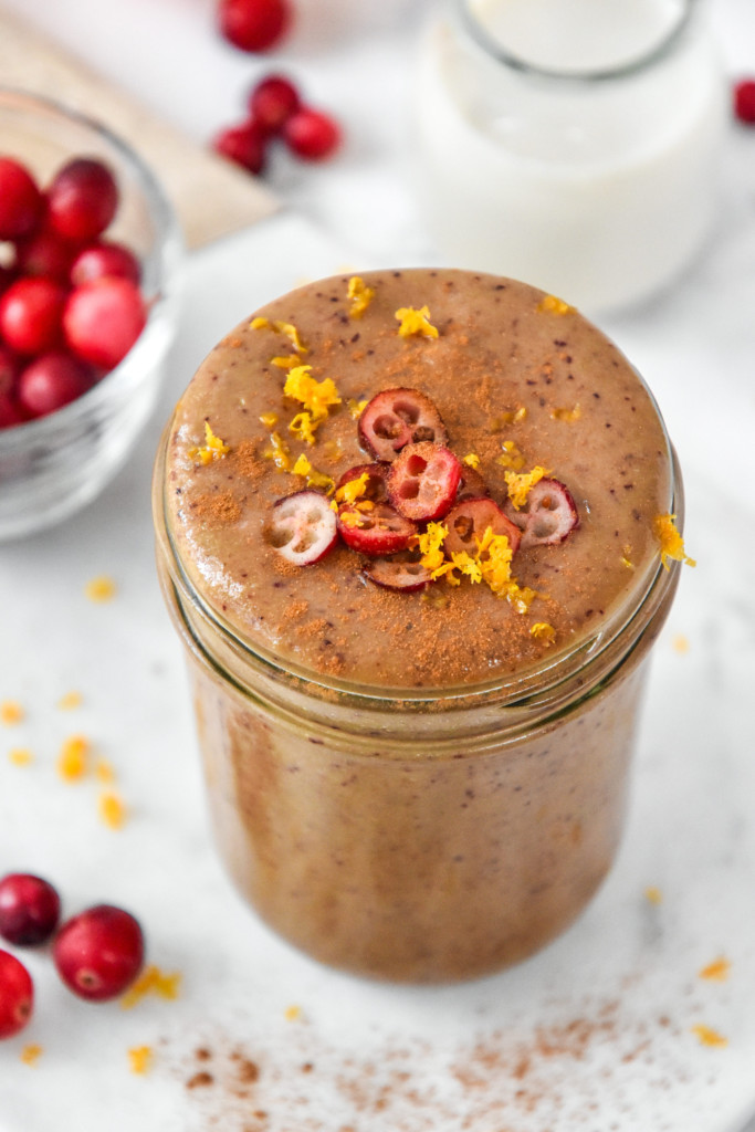 Cranberry Orange Cinnamon Holiday Smoothie topped with sliced cranberries and orange zest in a glass mason jar.