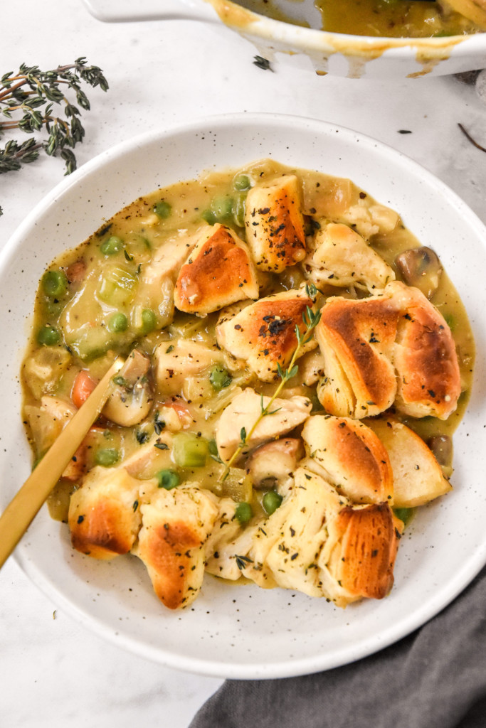 chicken pot pie with biscuit crust dished up in a bowl with a gold spoon.