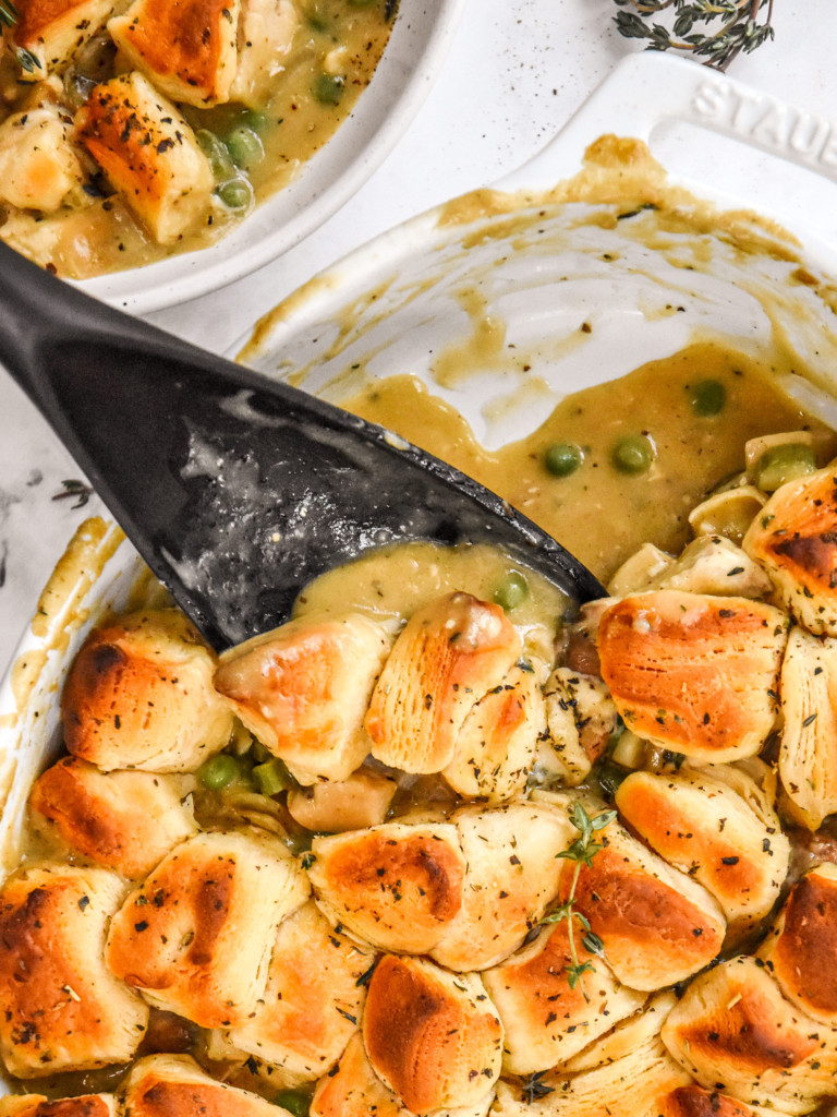 spoonful of chicken pot pie with biscuit crust in a white oval dish.