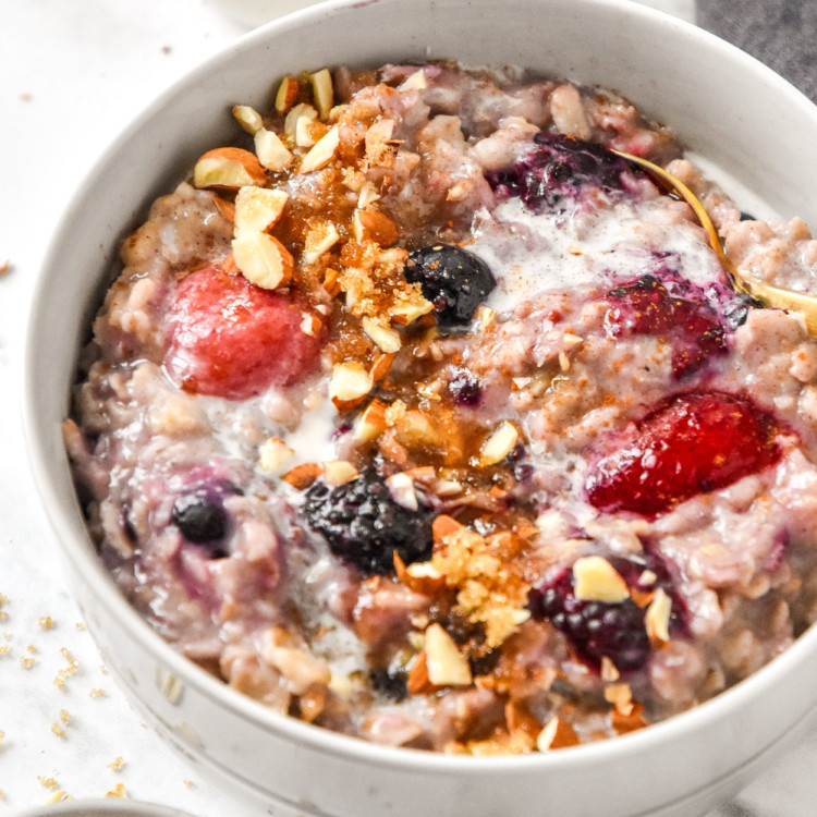 bowl of stovetop triple berry egg white oatmeal in a bowl with almonds on top.