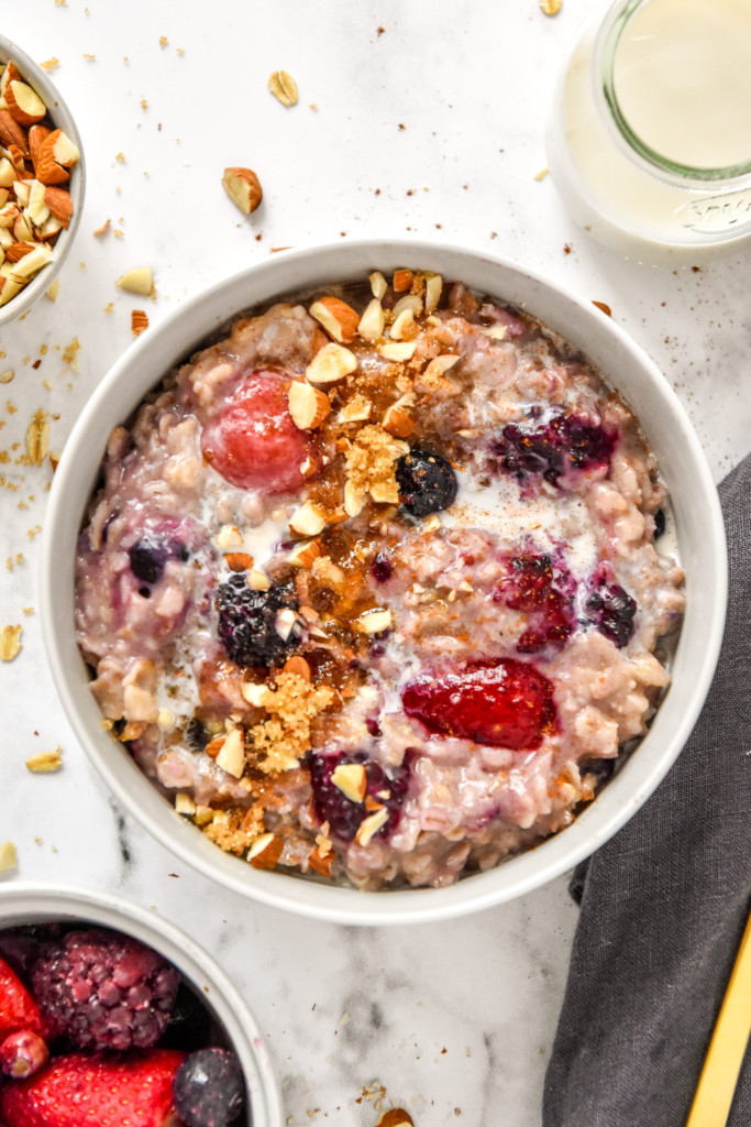 bowl of stovetop triple berry egg white oatmeal in a bowl with almonds on top.