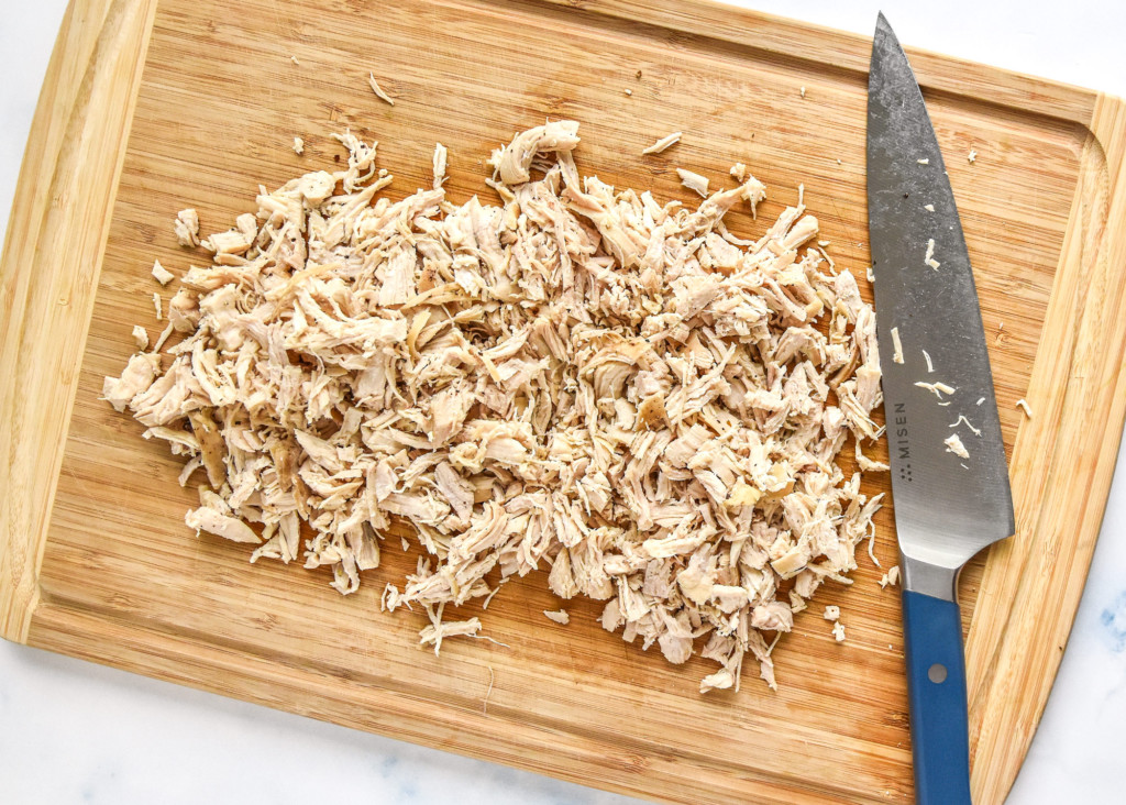 chopped chicken breast on a wooden cutting board.