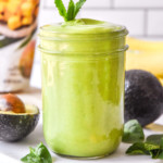 creamy avocado mint green smoothie in a mason jar with a mint leaf on top.