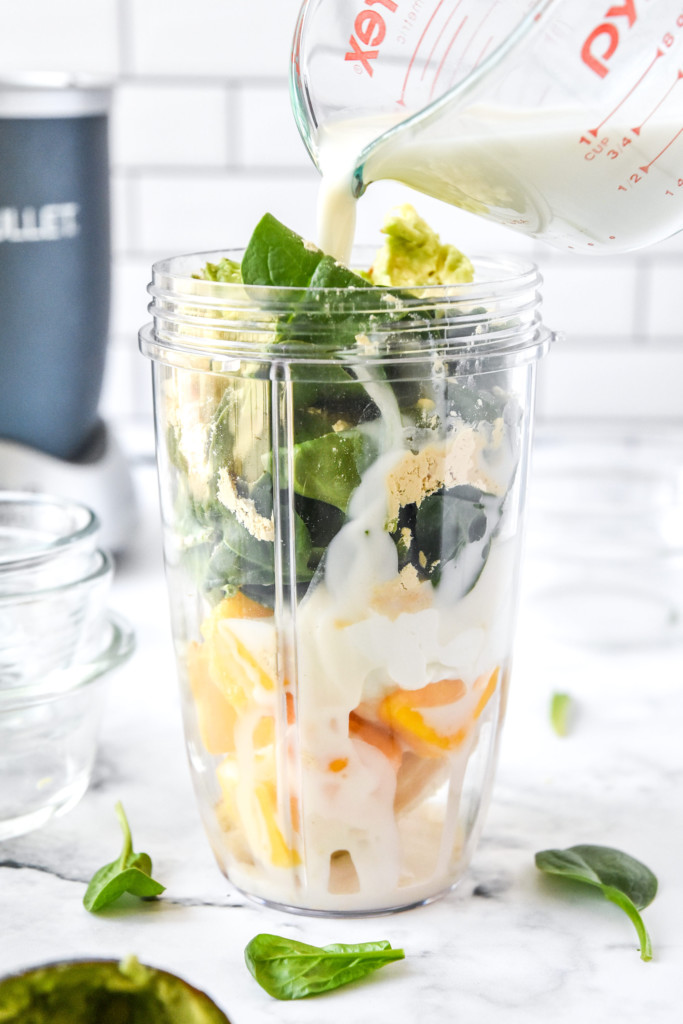 pouring milk into the blender container to make the smoothie.