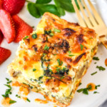 a serving on spinach feta chicken sausage breakfast casserole on a plate with strawberries.