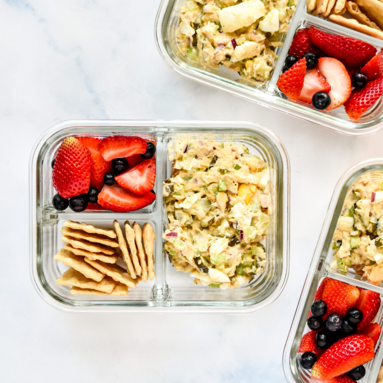 tuna egg salad meal prep with berries and crackers in glass meal prep containers.