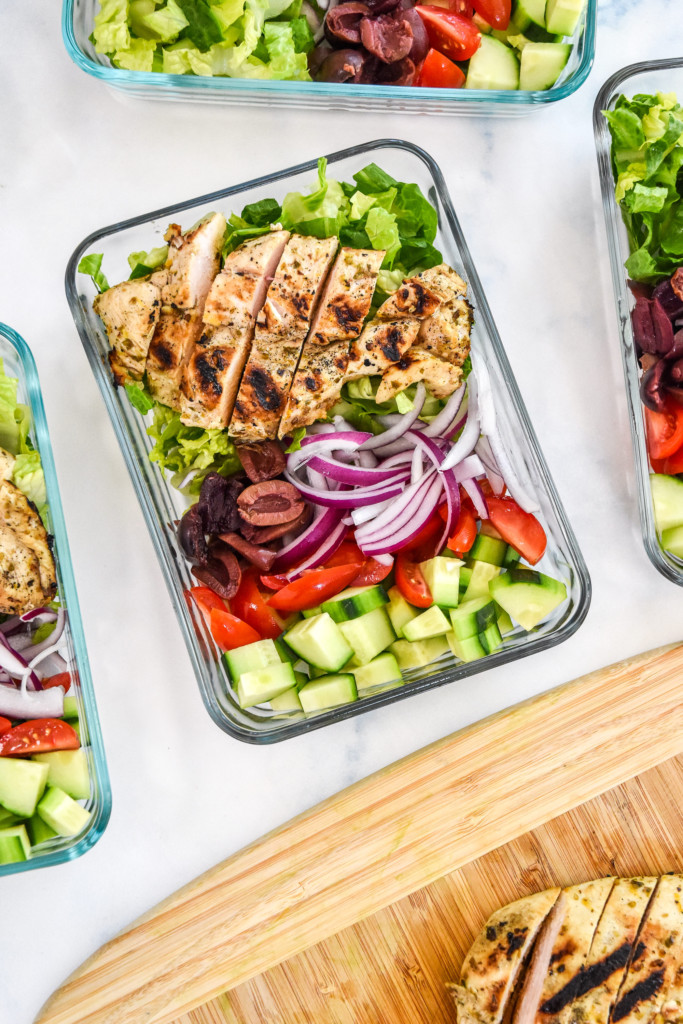 adding sliced chicken to the greek chicken salad meal prep bowls.