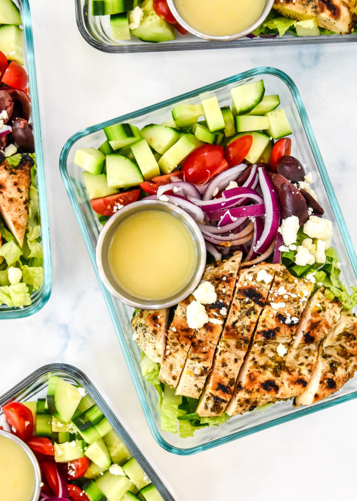 Greek chicken salad meal prep with dressing in a glass meal prep container.