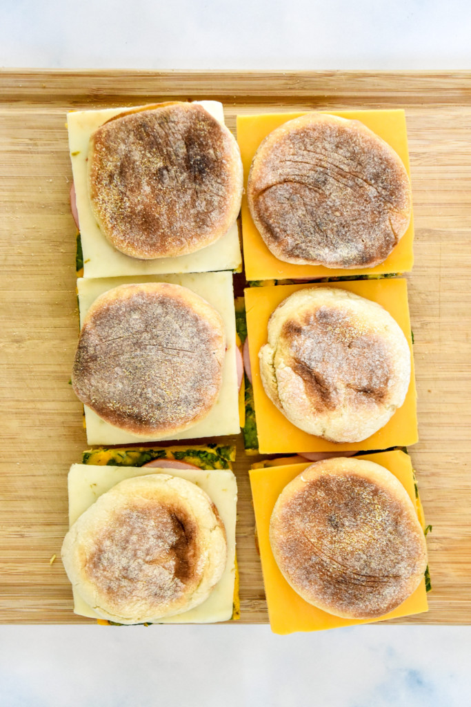 meal prepped breakfast sandwiches on a wood cutting board.