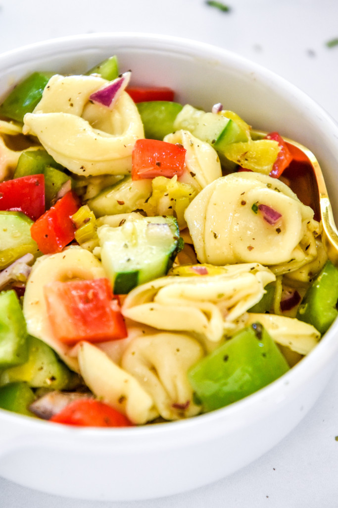 bowl of zesty italian tortellini pasta salad with a fork.