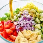 pouring italian dressing into the bowl of ingredients.