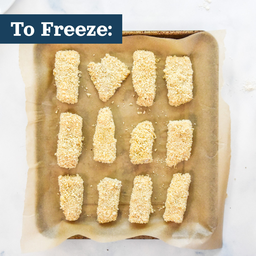 breaded fish sticks about to go into the freezer on a tray lined with parchment paper.