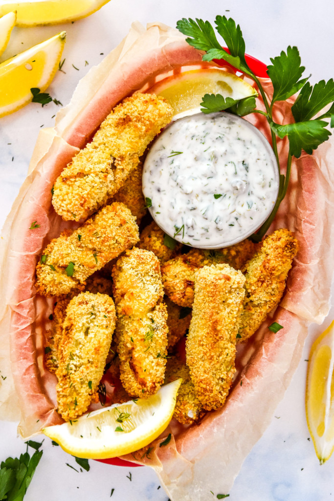 baked freezer-friendly fish sticks in a basket with tartar sauce.