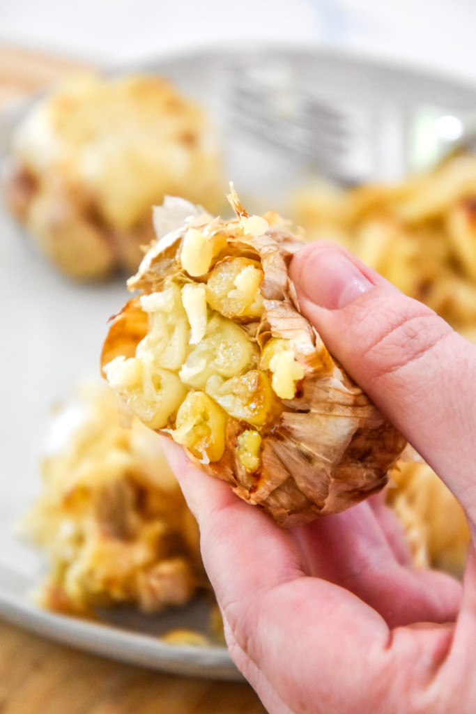 holding roasted garlic in hand and squeezing garlic out.