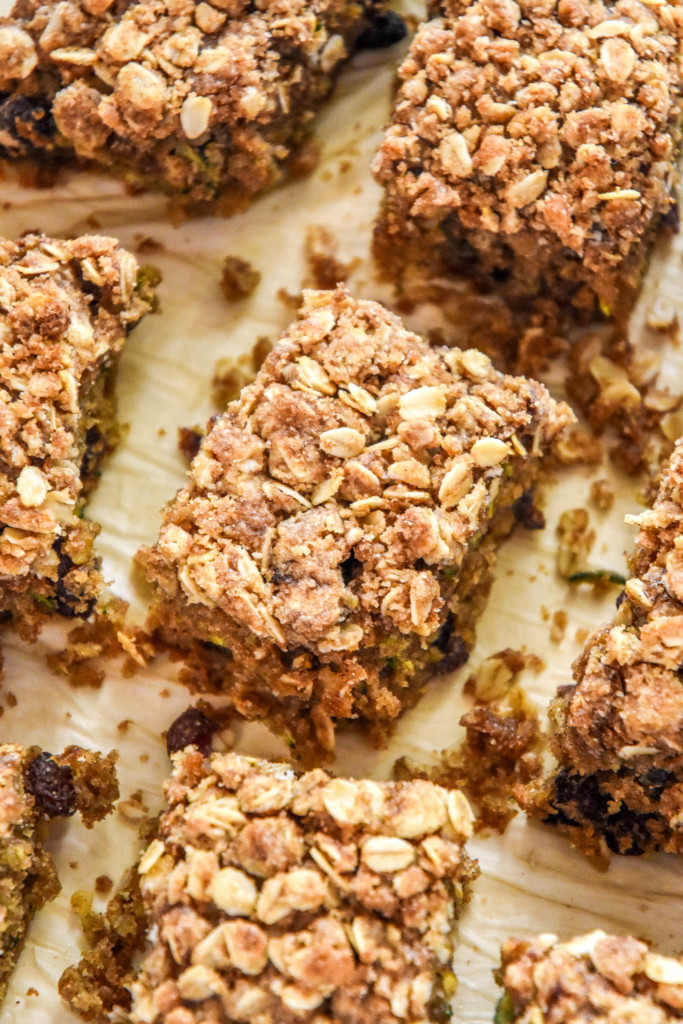 cinnamon raisin zucchini coffee cake cut into pieces on parchment paper.
