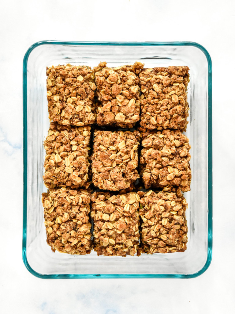 cinnamon raisin zucchini coffee cake cut pieces in a glass pyrex dish for storage.