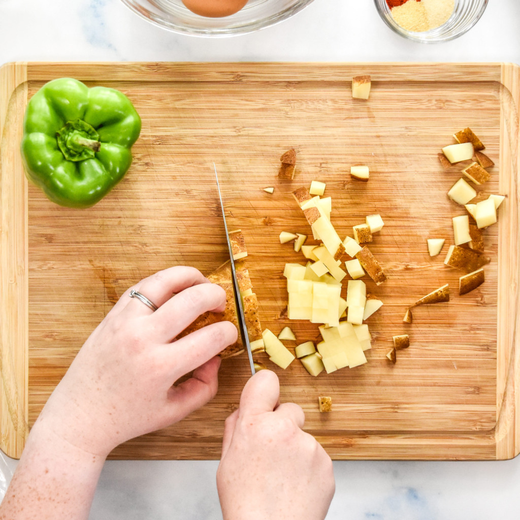 dicing potatoes on a wooden cutting board.