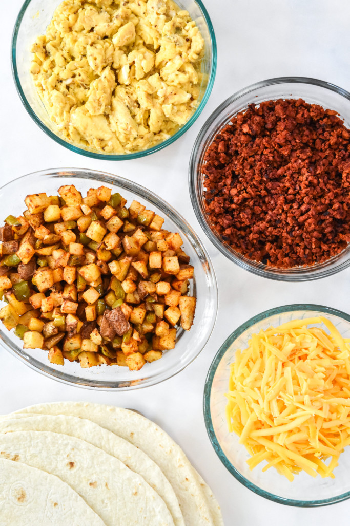 all the cooked fillings ingredients in bowls for the meal prep soy chorizo breakfast burritos.