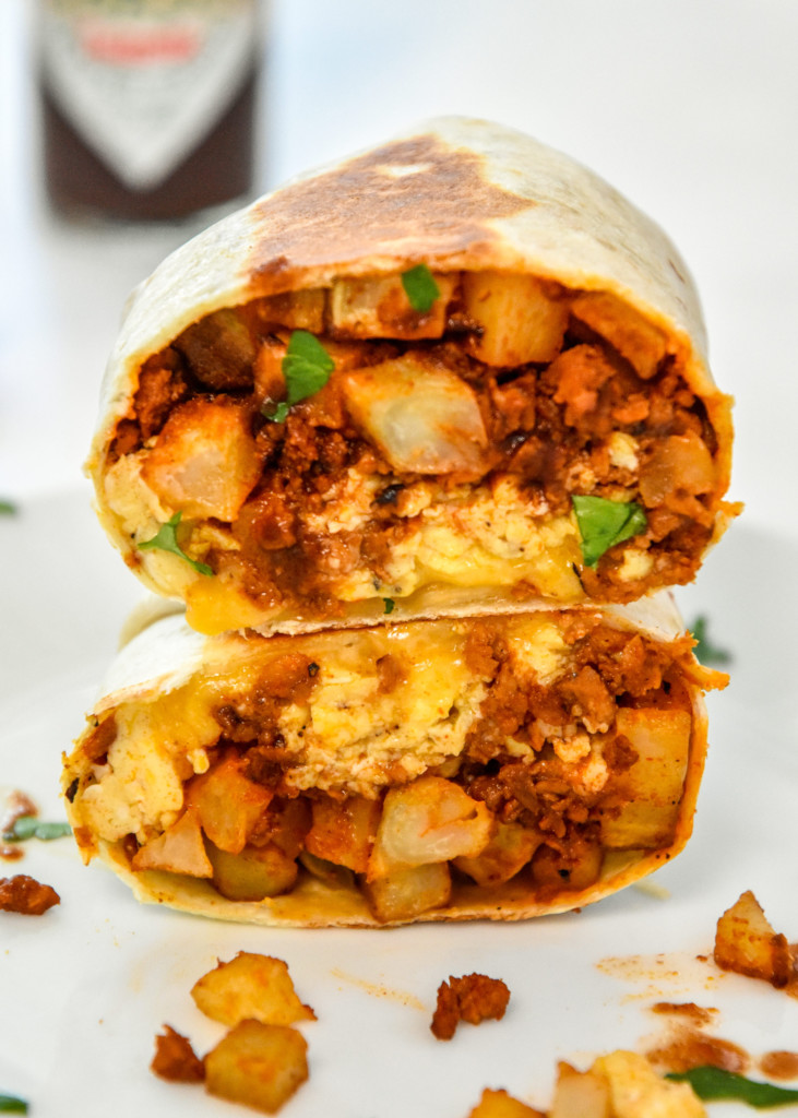 meal prep soy chorizo breakfast burritos cut in half and stacked on a plate.