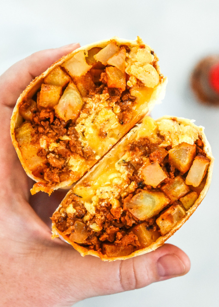 holding a cut soy chorizo breakfast burrito in hand.