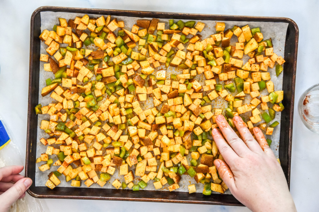 spreading the potatoes and peppers in a single layer on a sheet pan.