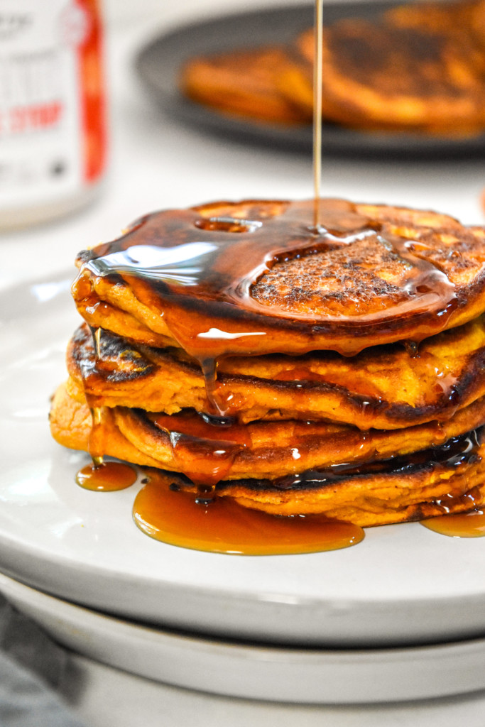 pouring syrup on the pumpkin pie greek yogurt pancakes.