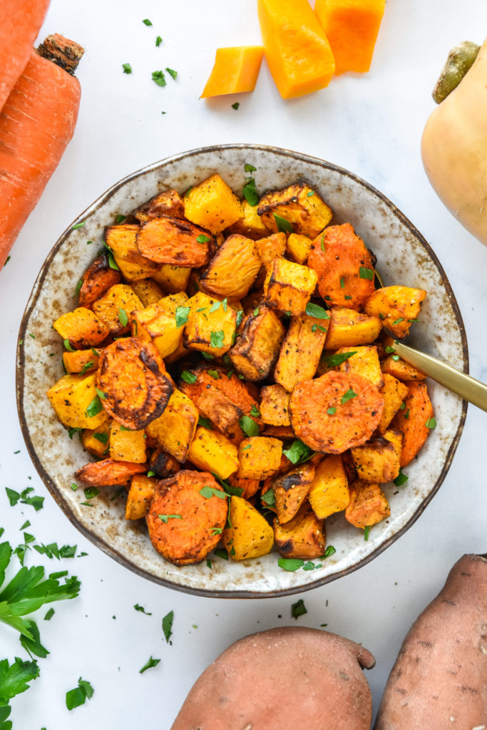 air fryer roasted seasonal vegetables in a bowl with a spoon.