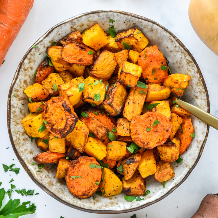 air fryer roasted seasonal vegetables in a bowl with a spoon.