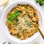 Ground Turkey Zucchini Orzotto with fresh basil on top in a white bowl with fork.
